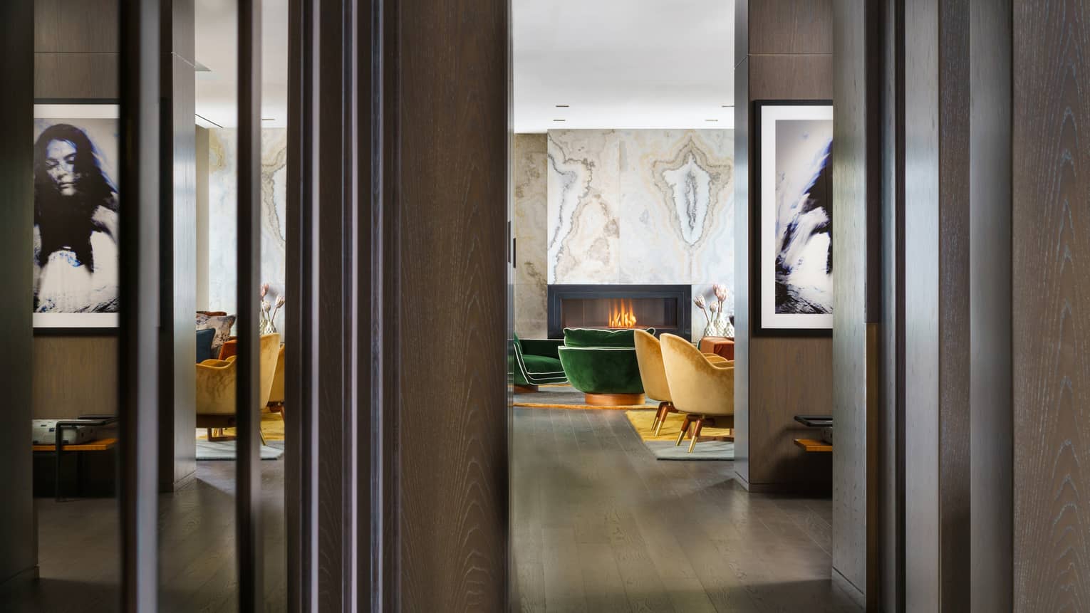 Entryway to suite, dark wood floors, mustard- and emerald green-coloured arm chairs by fireplace