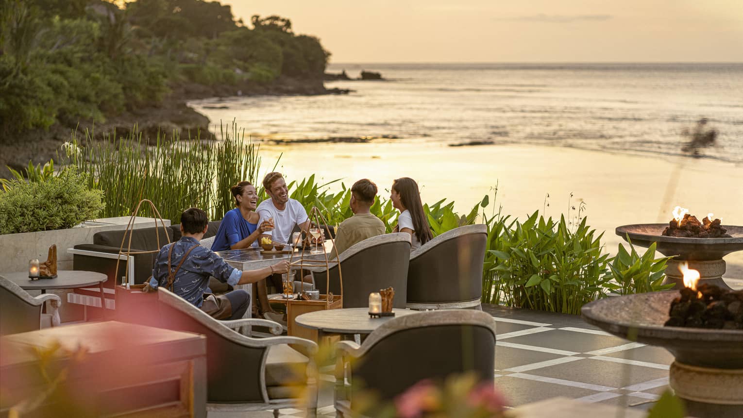 Group of friends laugh and enjoy cocktails at Sundara at sunset
