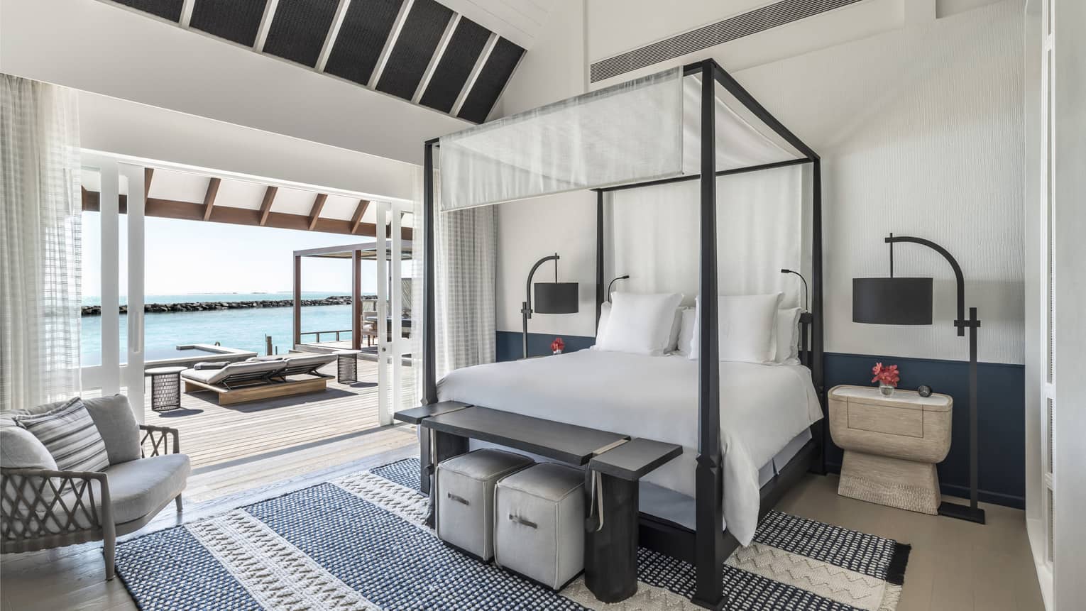Bedroom with four-poster canopied bed with doorway leading to pool deck with cabana