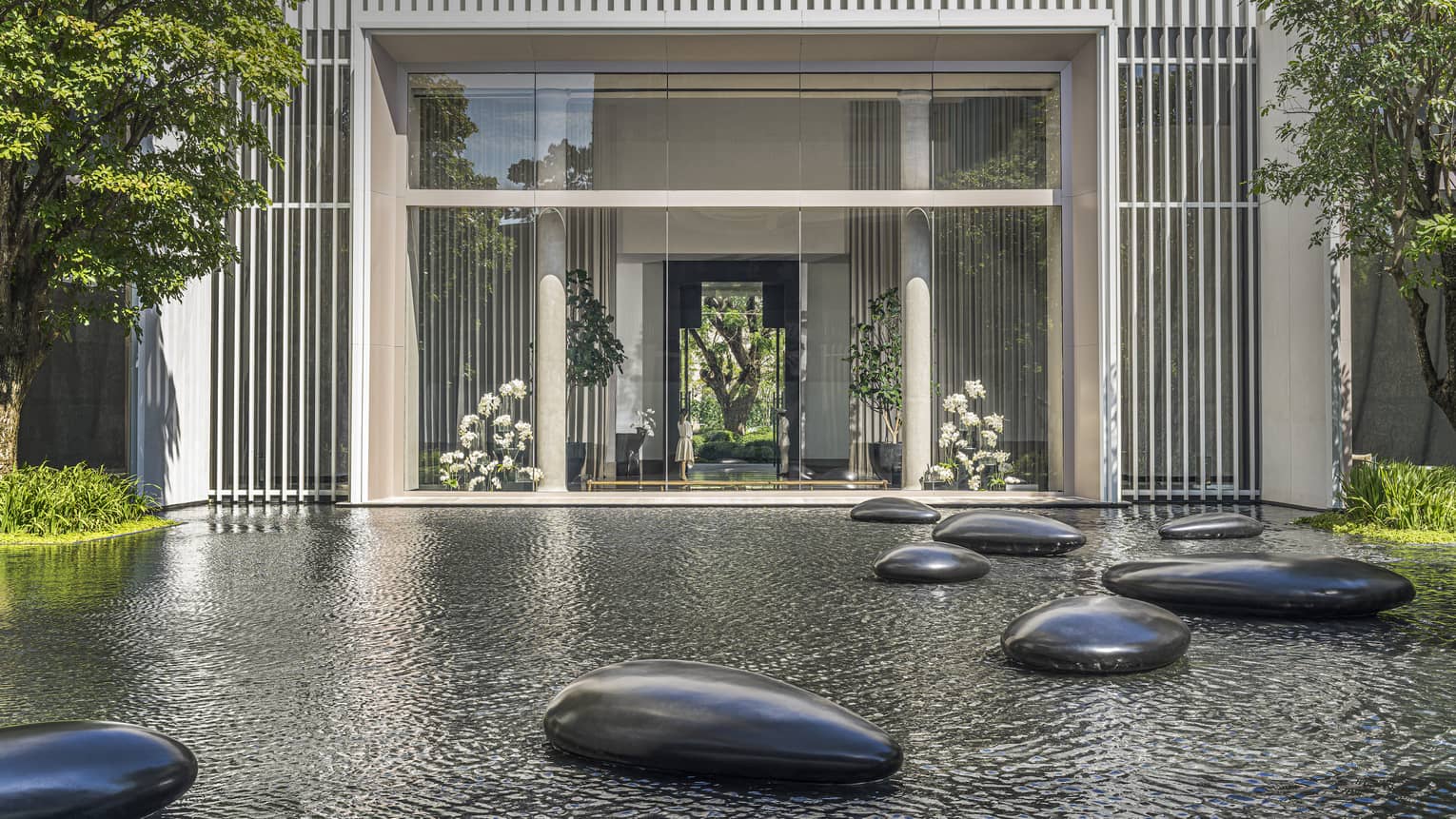 Calm pond in front of hotel with large polished stones scattered throughout