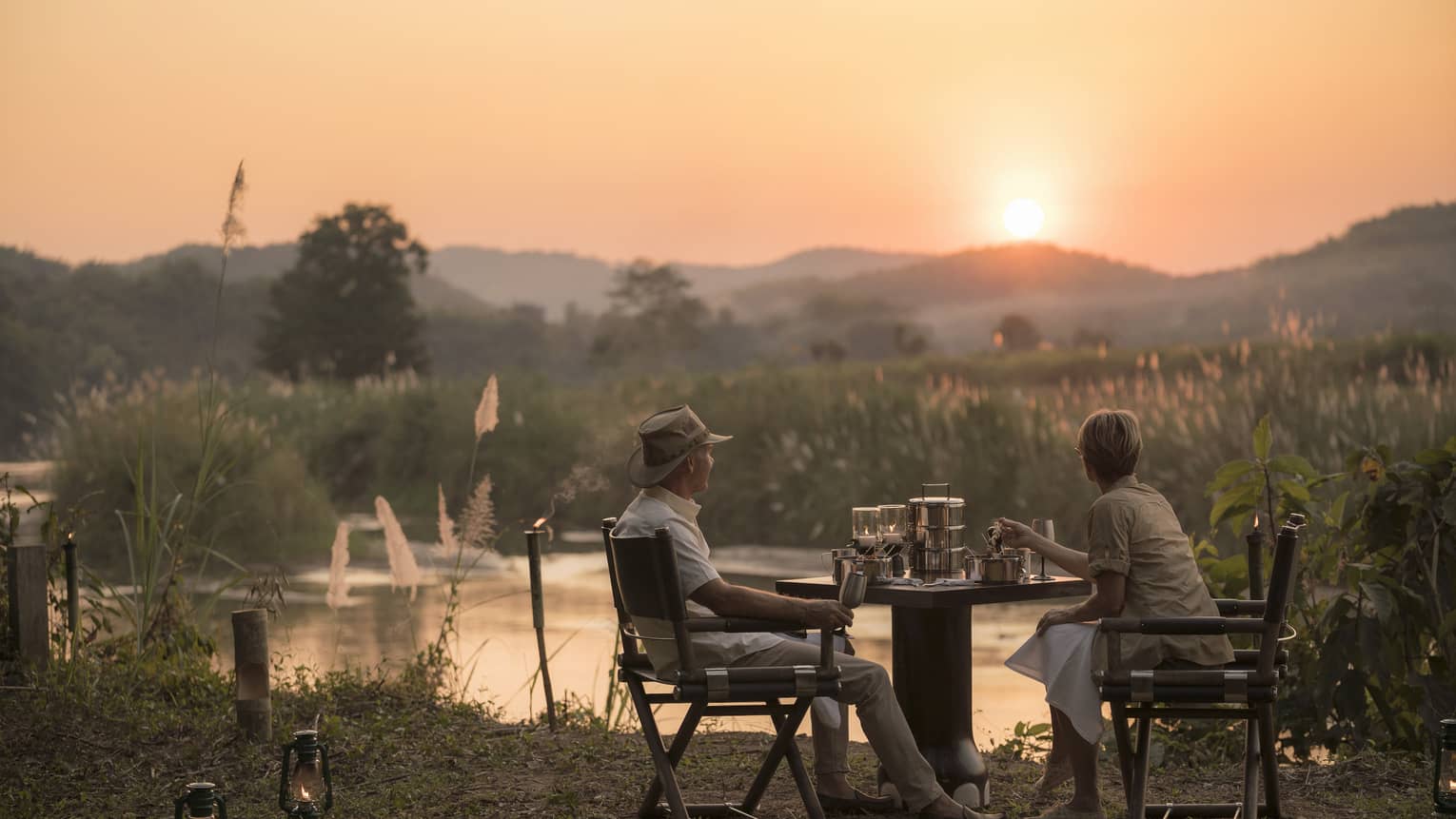 Couple enjoys Camp Bush Dinner along river at sunset