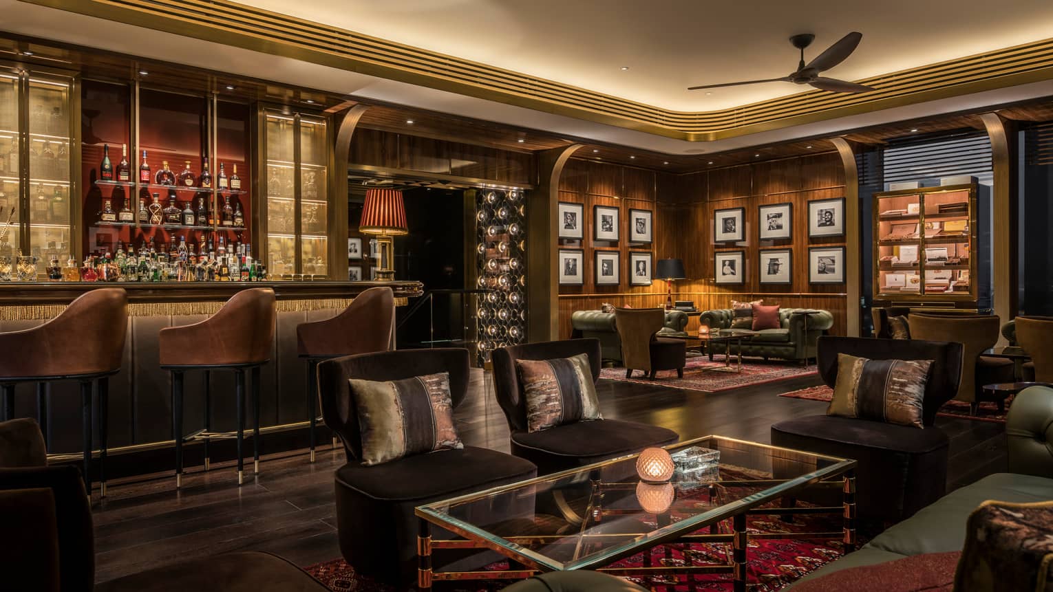 Churchill Club dimly-lit lounge, sofa chairs, bar with stools, dark brown and wood decor 