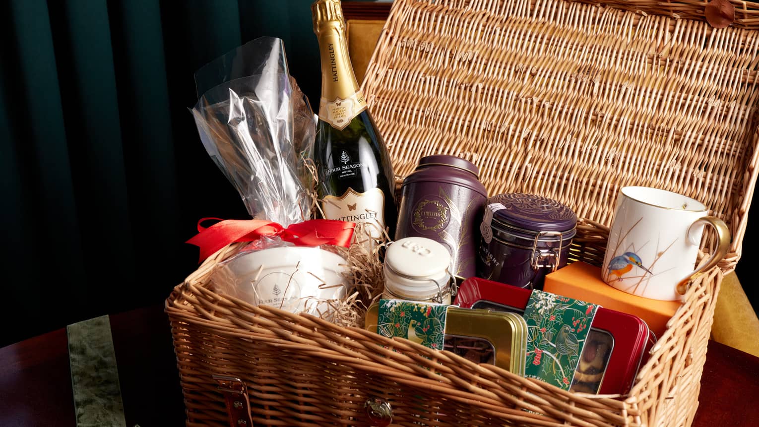 Picnic hamper filled with champagne bottle, jarred teas, mug, and assorted nuts and candies,Picnic hamper filled with champagne bottle, jarred teas, mug, and assorted nuts and candies