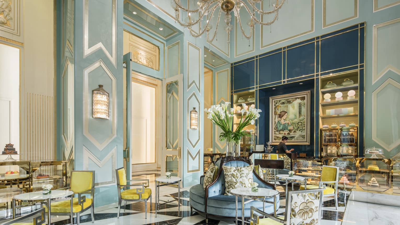 Bright La Patisserie cafe with elegant blue decor, yellow chair, high ceilings, crystal chandelier