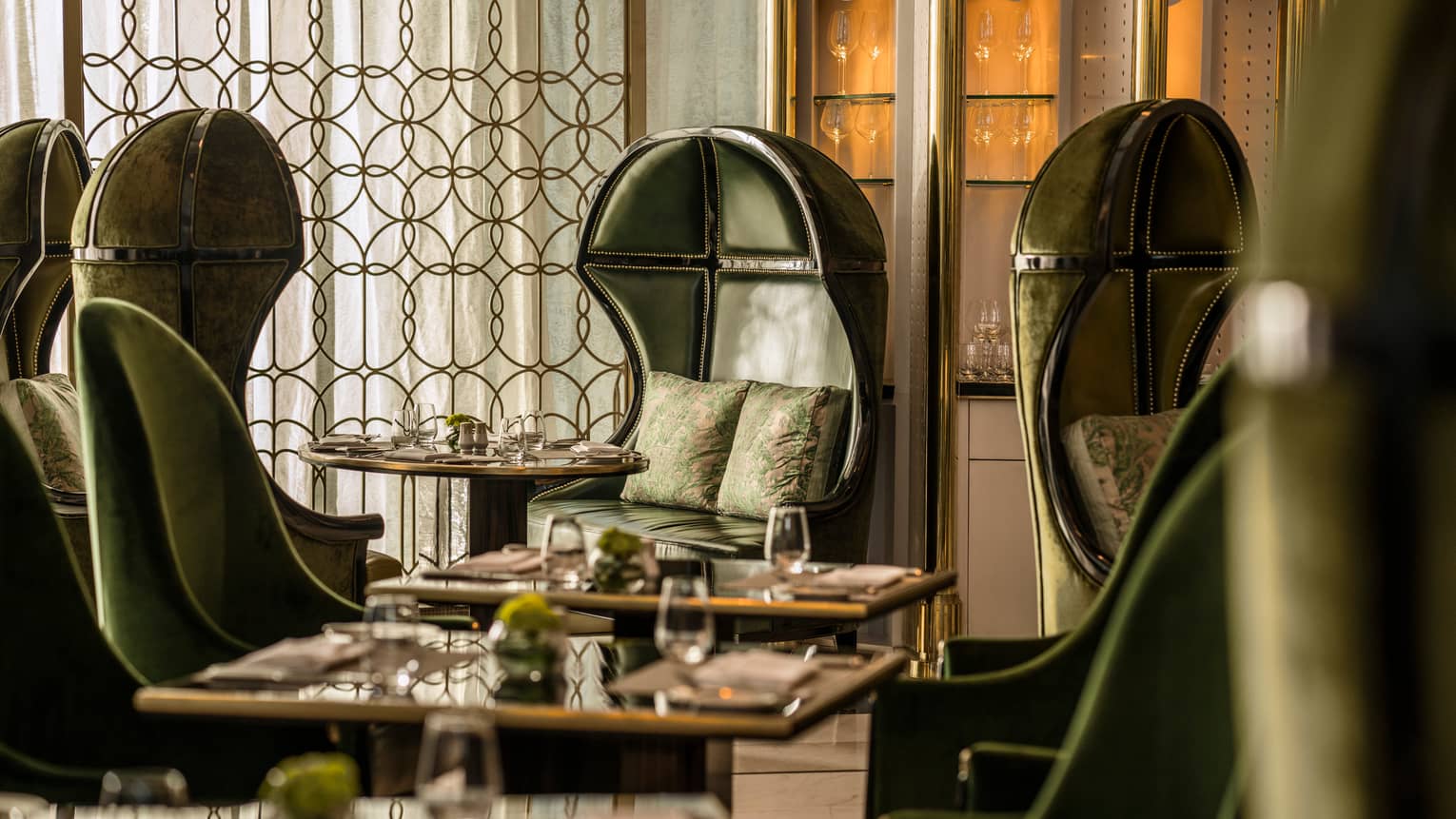 Premier Club booth with dark green leather bucket chairs, accent pillows, decorative brass screen