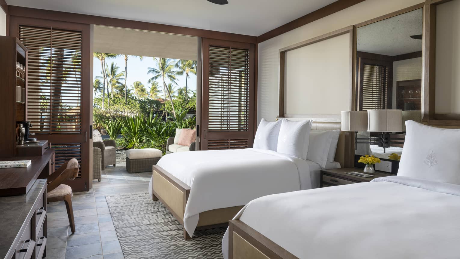 Hotel room with two double beds, ceiling fan, walk-out terrace with greenery