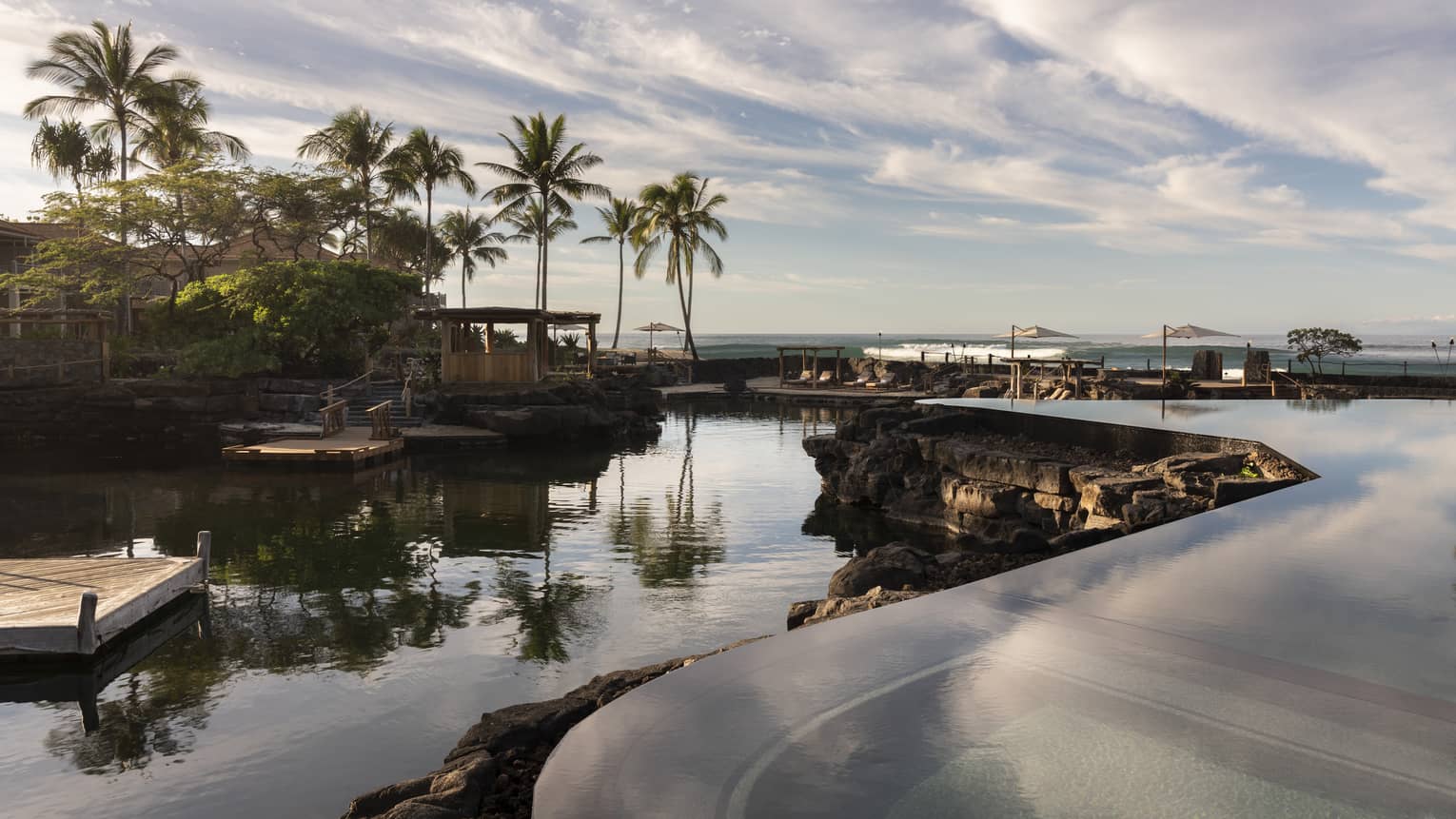 Resort pool that mimics a curved pond, palm trees in distance