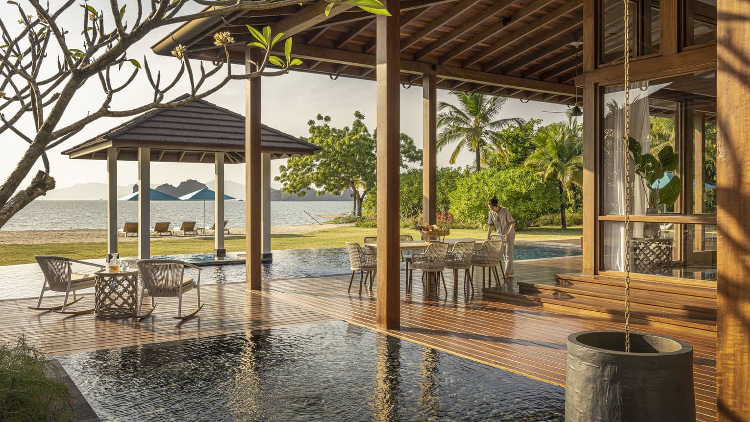 Private pool terrace and wooden deck under pergola, looking out to green lawn and Langkawi beach