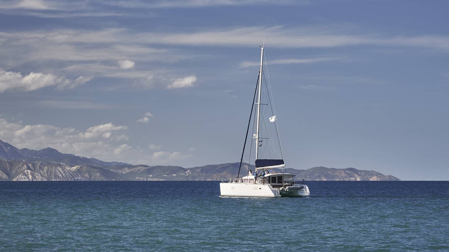 A boat sailing on the ocean with mountains in the distance.