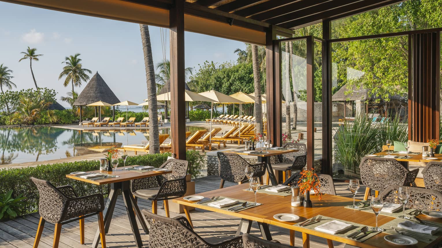 Open-air restaurant Caf� Huraa with rattan chairs and blonde wood tables, overlooking the pool