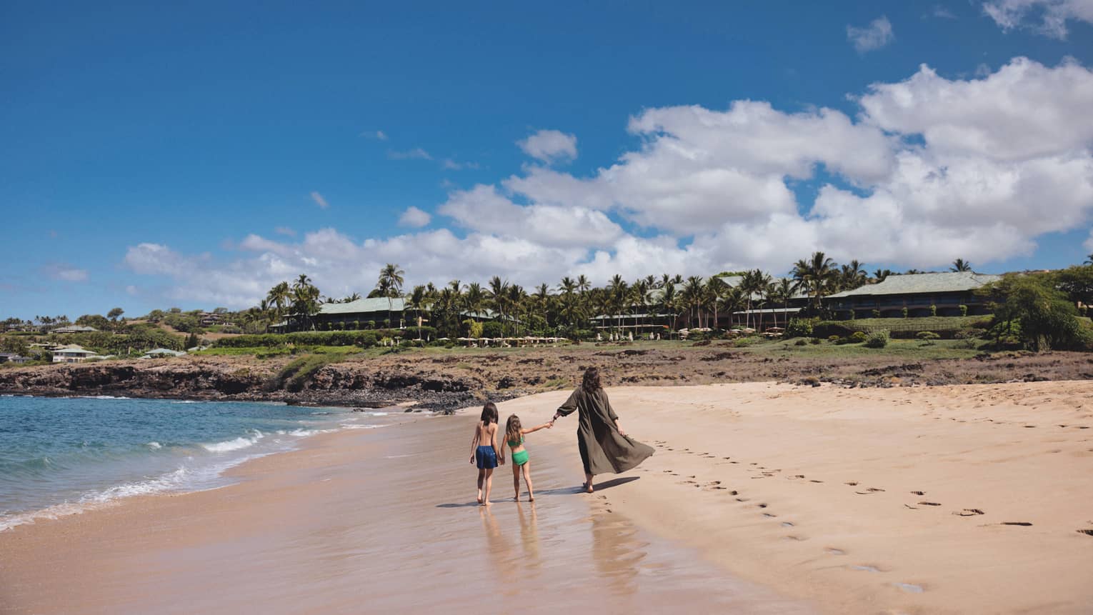 Woman and two kids walk on the beach
