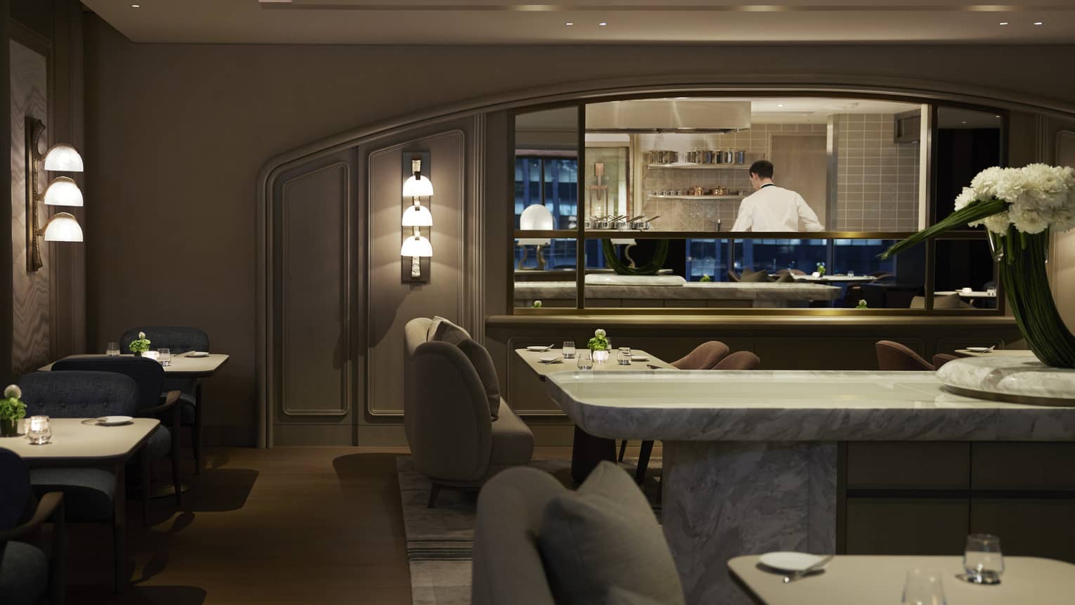 Dimly lit intimate dining area with lighted wall sconces, dark grey colour scheme
