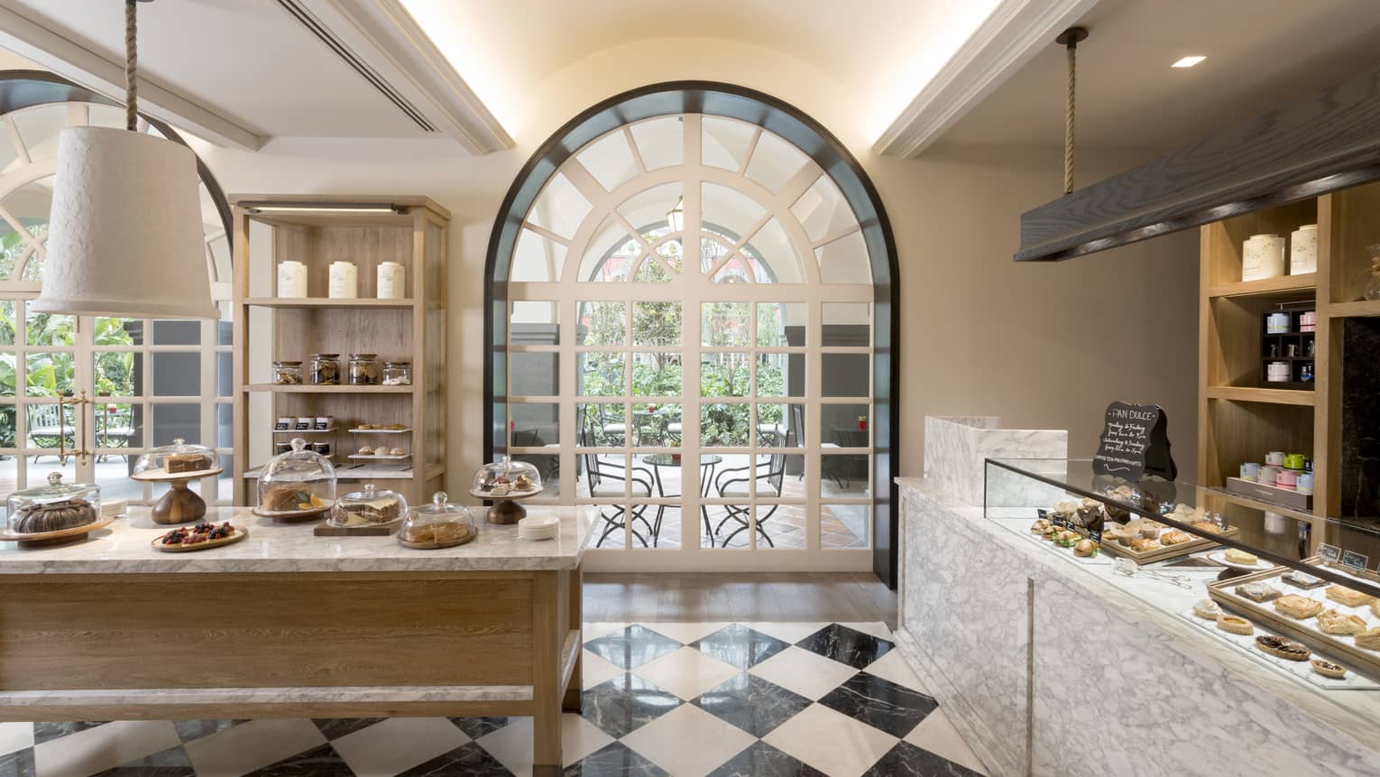 A brightly lit store with pastries, large windows and checkered floors.