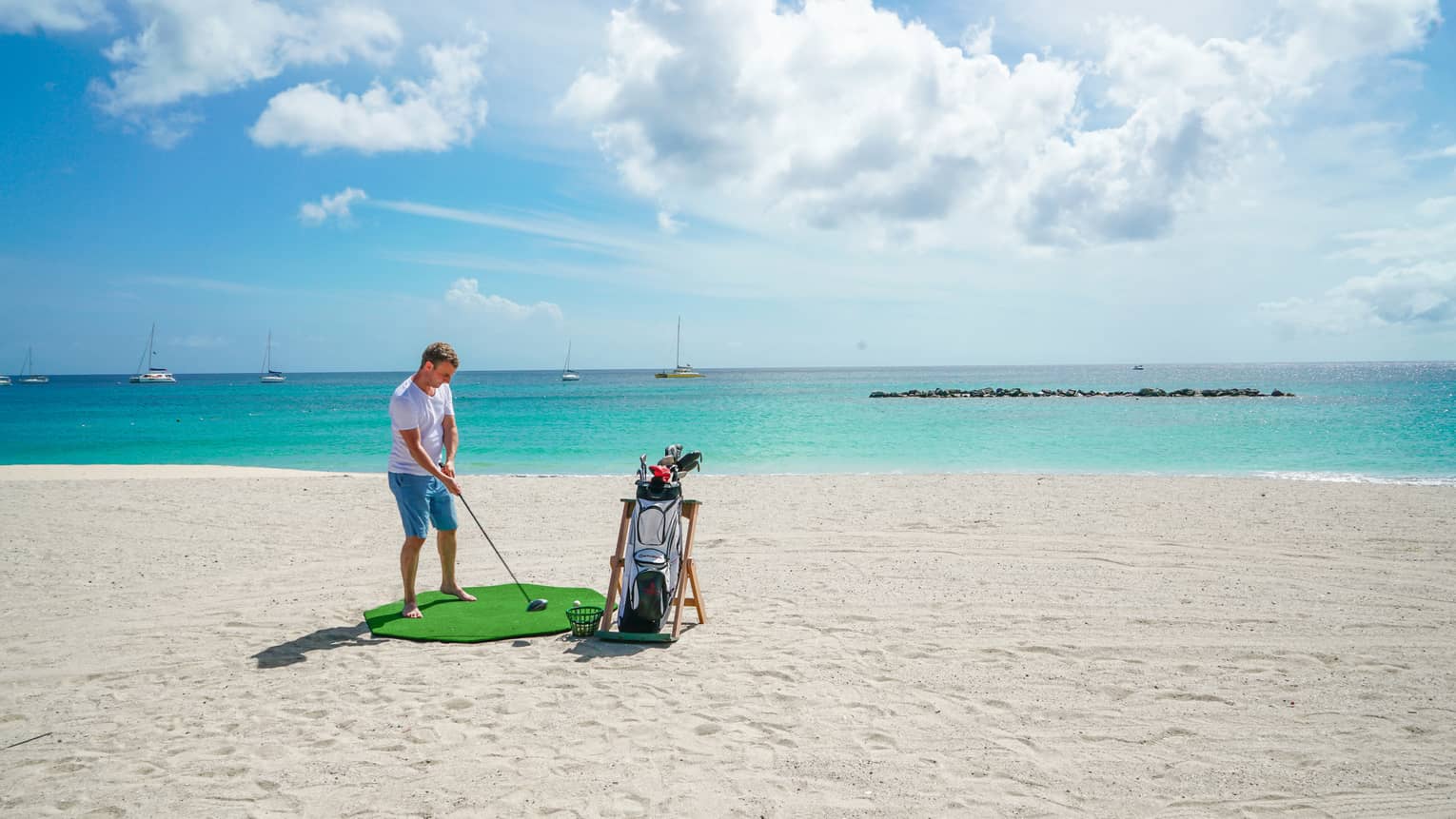 A man golfing on a clean beach near the ocean.