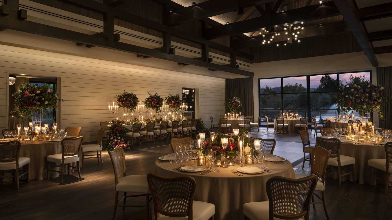 Banquet tables set for wedding in dimly lit barn