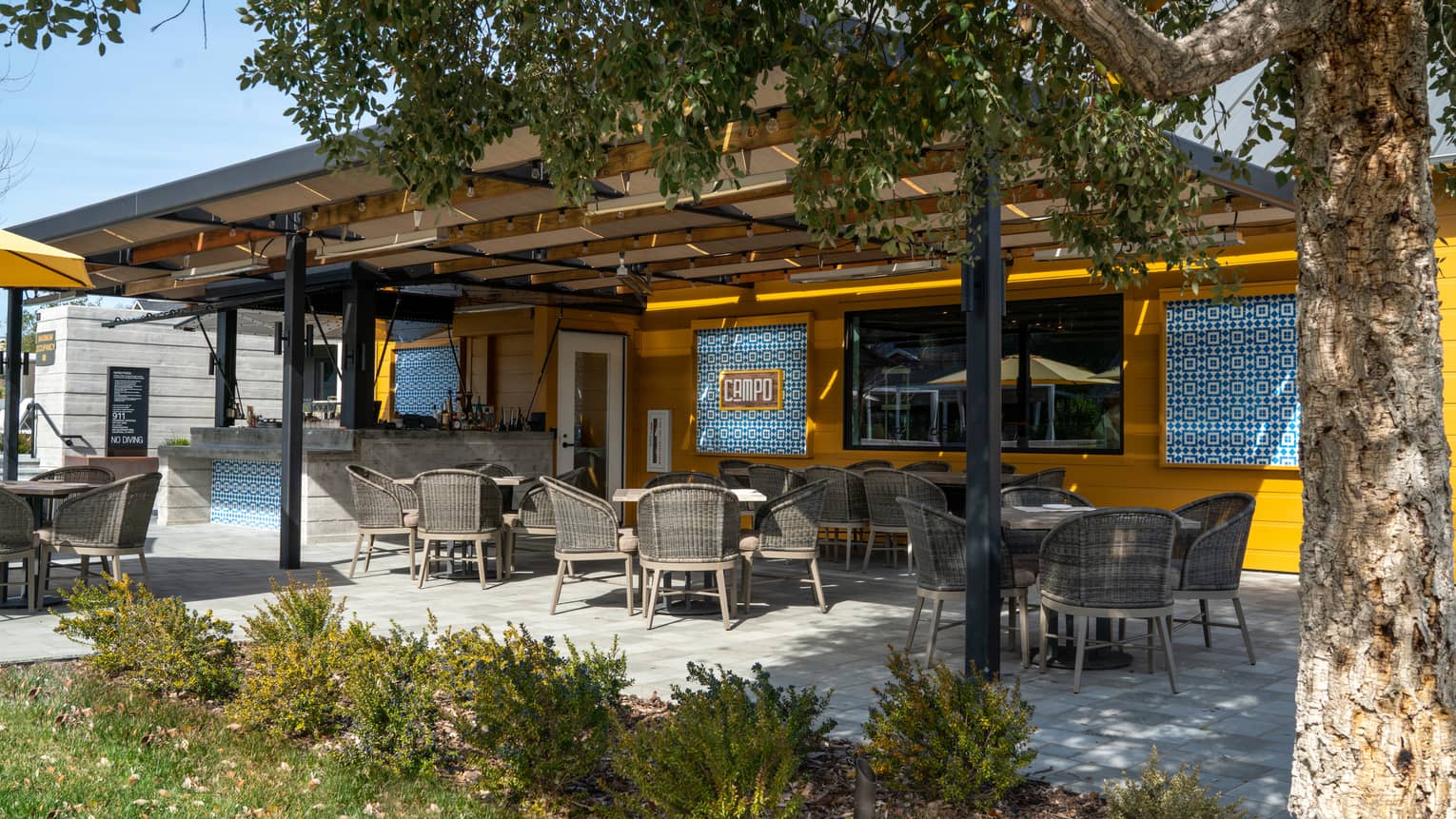 A covered outdoor eating area near grass and trees.