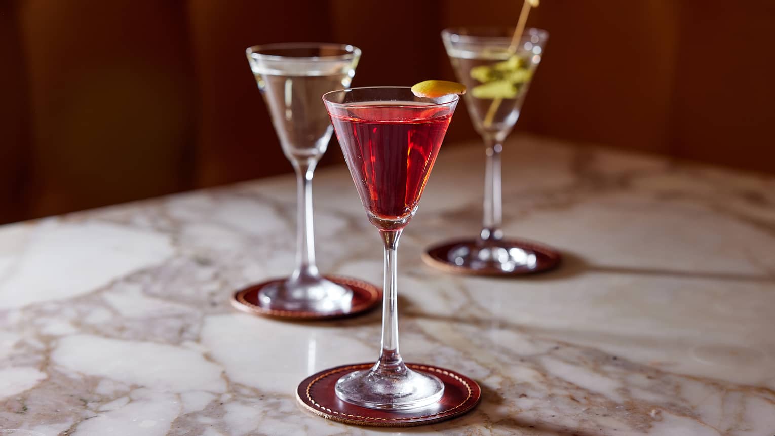 Trio of cocktails in cordial glasses; one clear, one red, one yellow