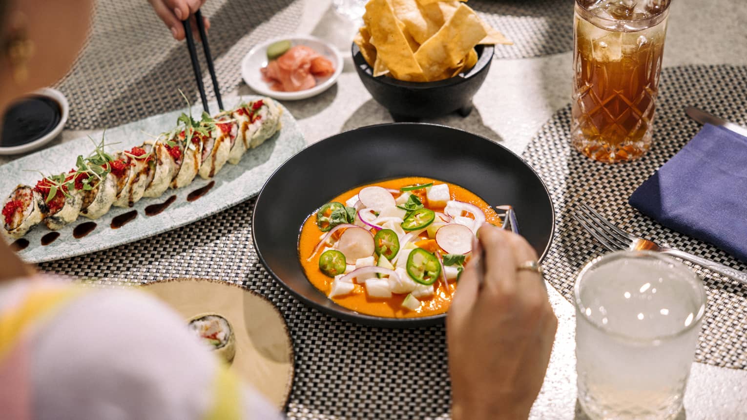 Gazpacho and sushi on table with cocktails
