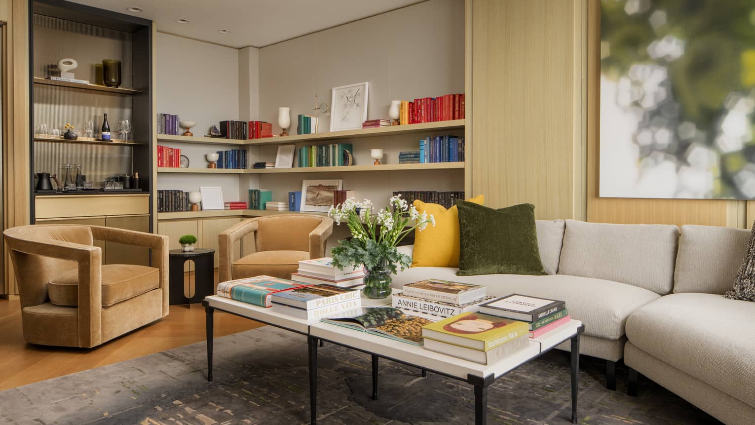 Office and living area of guest room with cream sofa, tan armchairs and built-in bookshelves