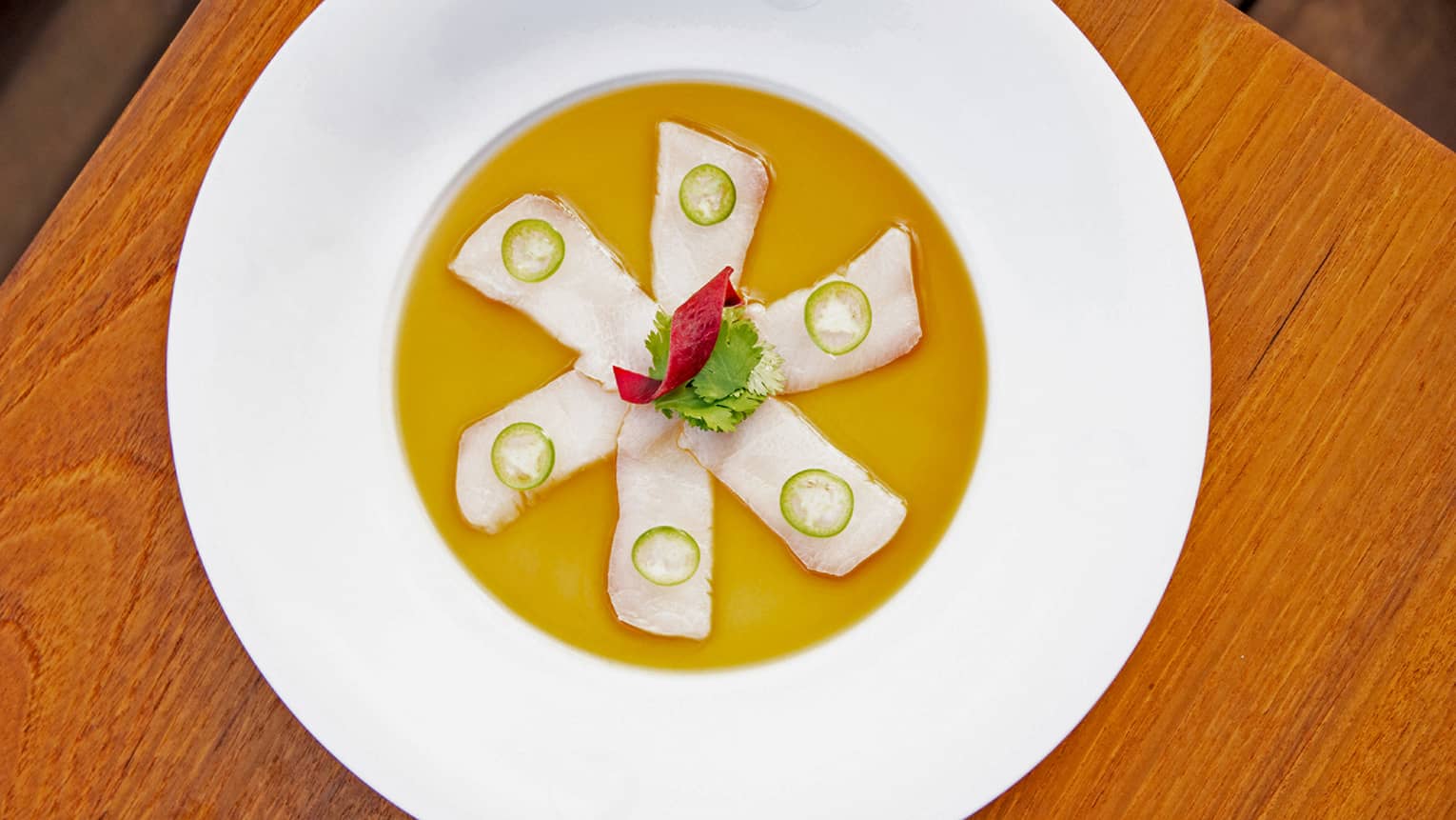 Raw fish delicately plated with jalapeno and sauce