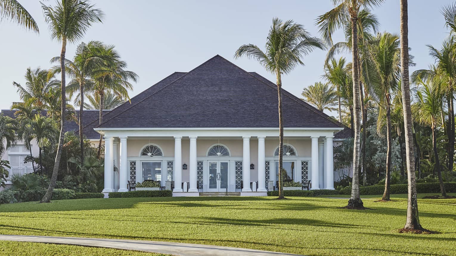 View across green lawn to bungalow with white pillars