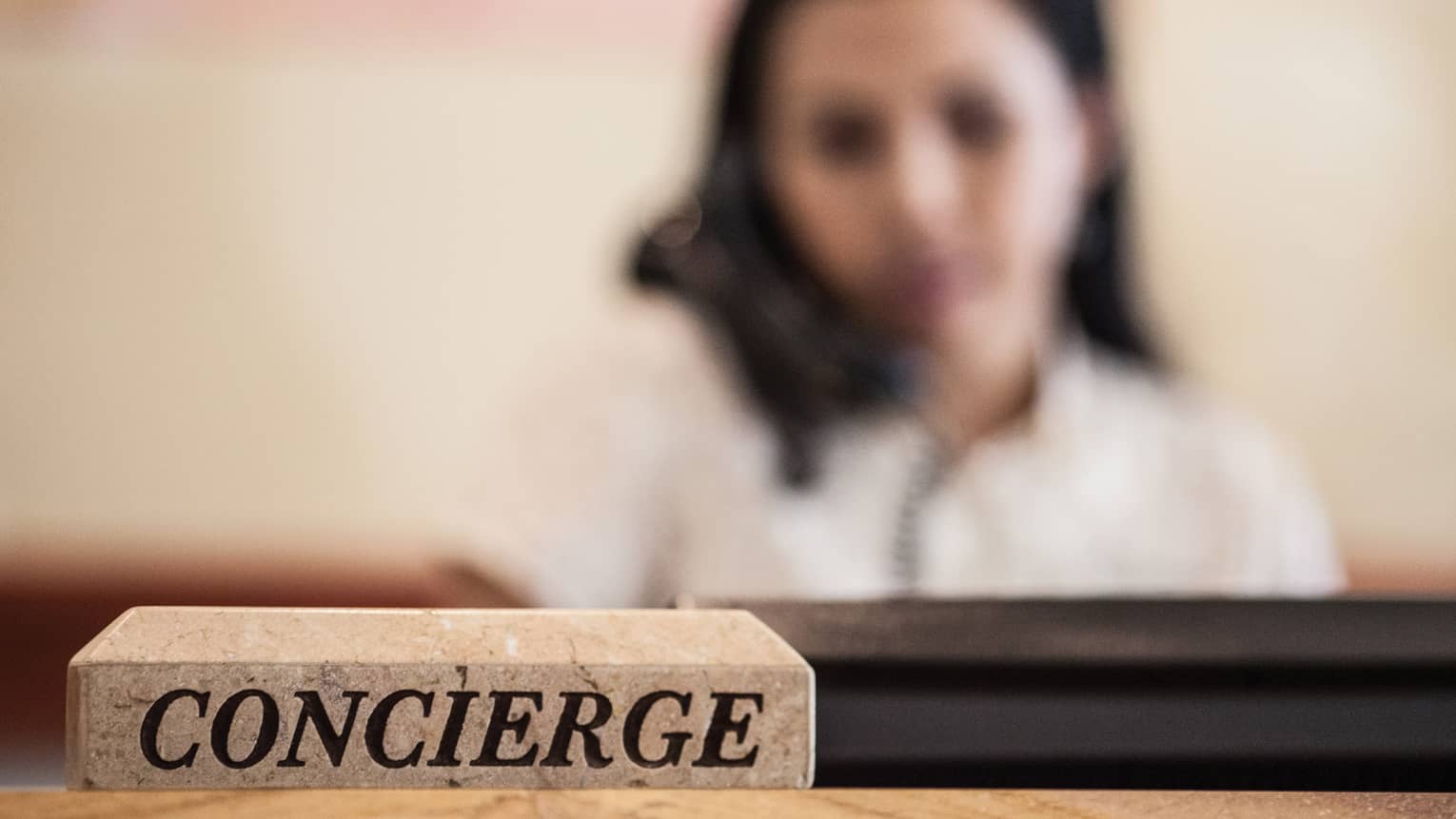 Woman on the phone behind a Concierge desk