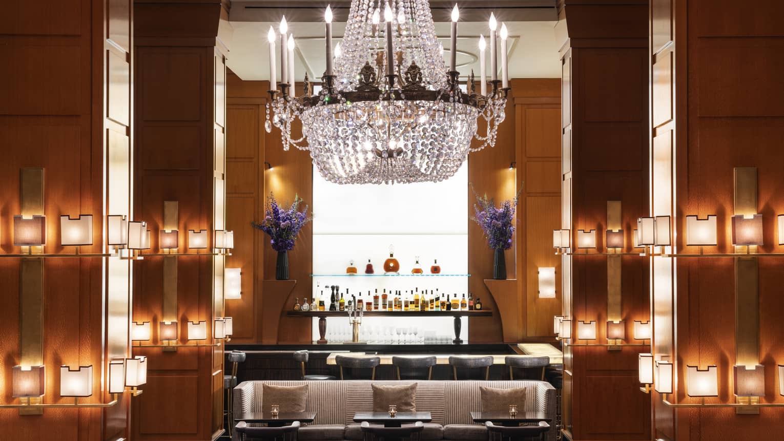 A bar area with a large chandelier and small lights on the walls.