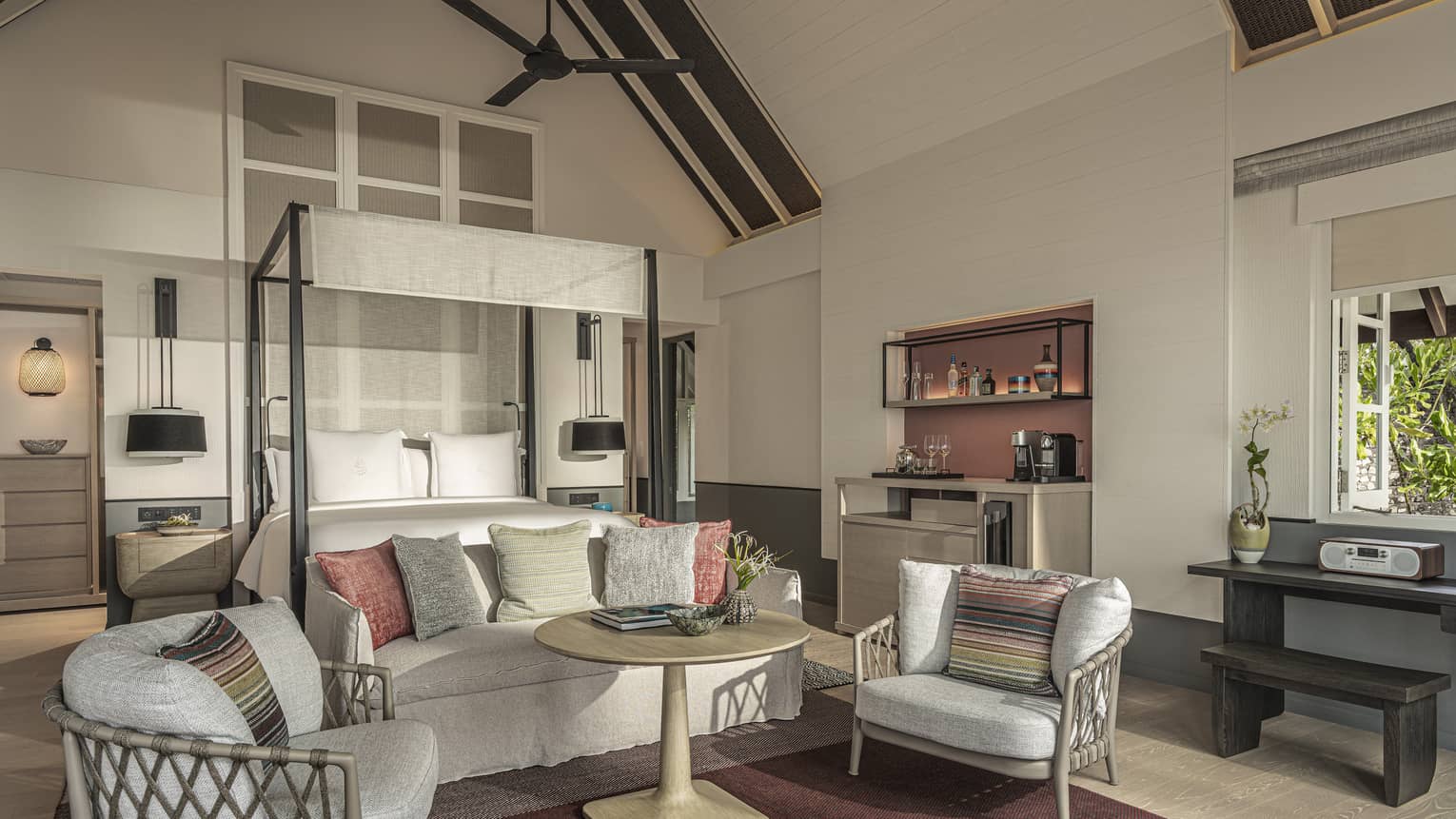 Master bedroom with canopy bed, sofa and two chairs, with vaulted beamed ceiling