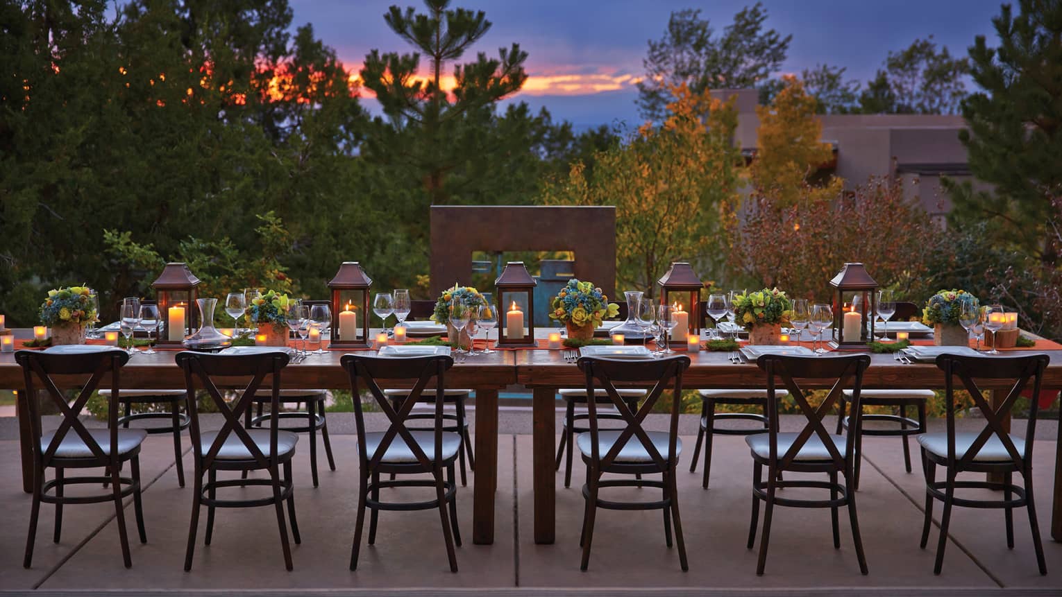 Long, candle-lit dining table on Terra patio at sunset