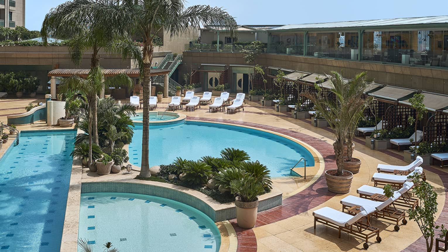Aerial view of blue-water circular pool with lounge chairs and palm trees