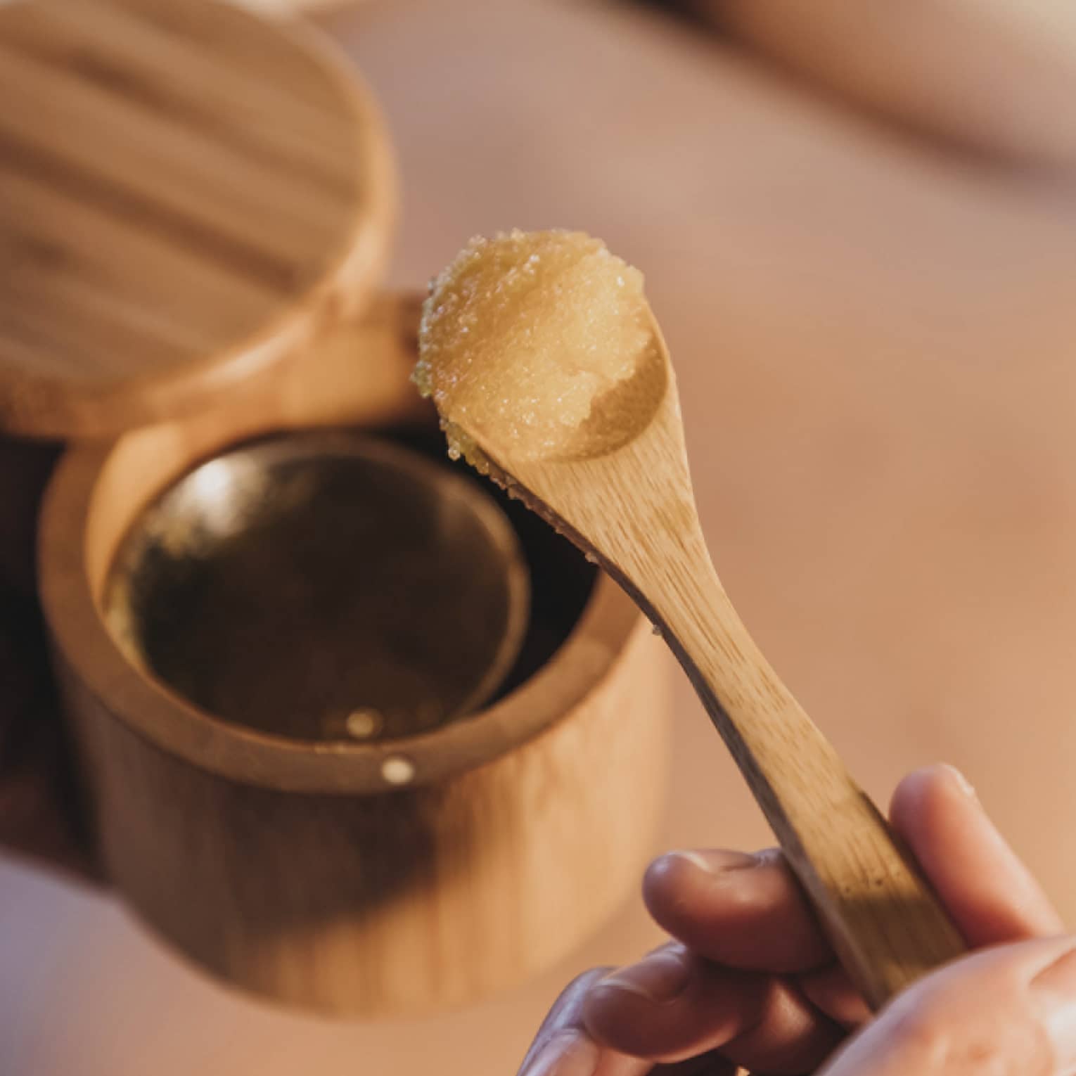 A spa member removing a spa treatment ingredient from a wooden cup with a spoon.