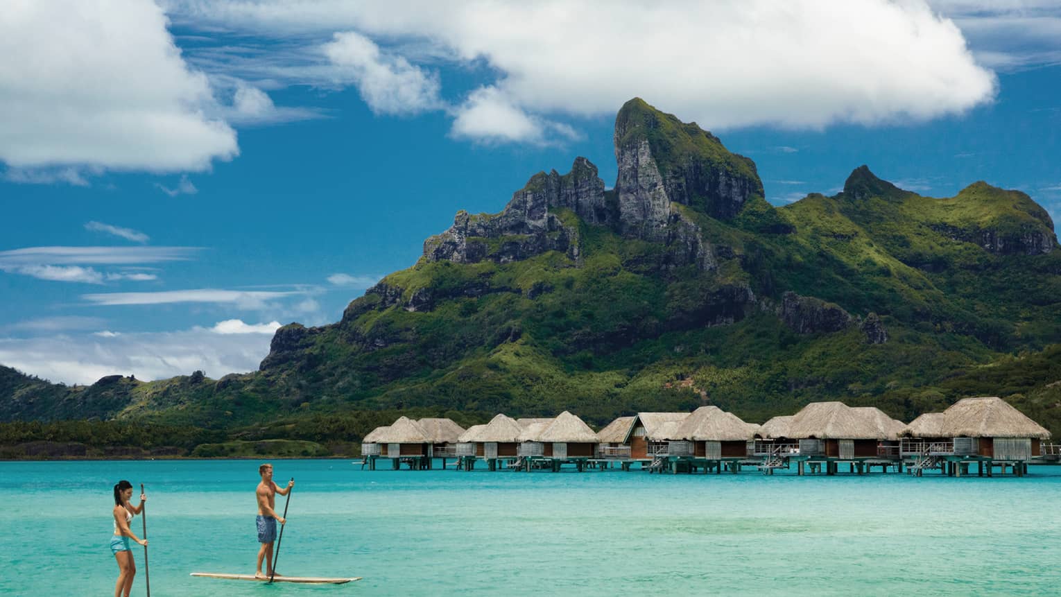 Two guests stand-up paddleboarding in a Bora Bora lagoon