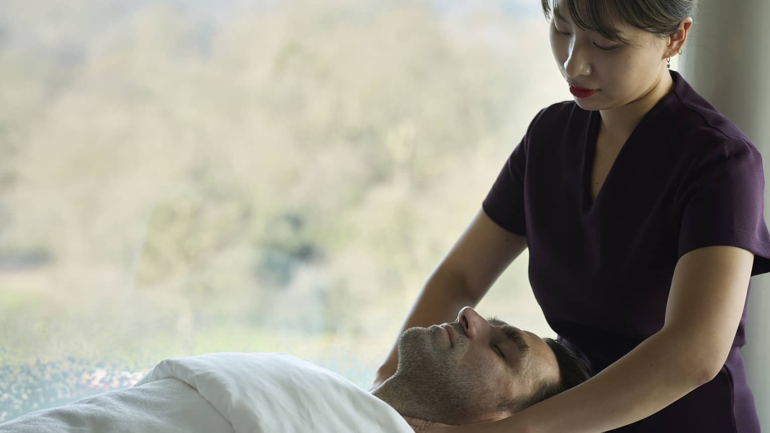 Spa therapist treating guest lying on spa table