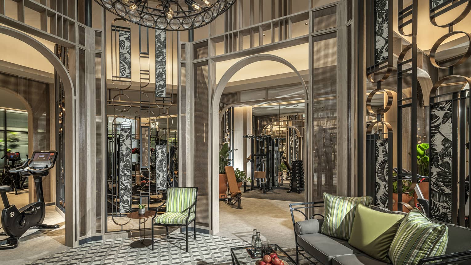 Fitness Centre lobby with high ceilings, round wrought-iron chandelier, sofa with green accent pillows