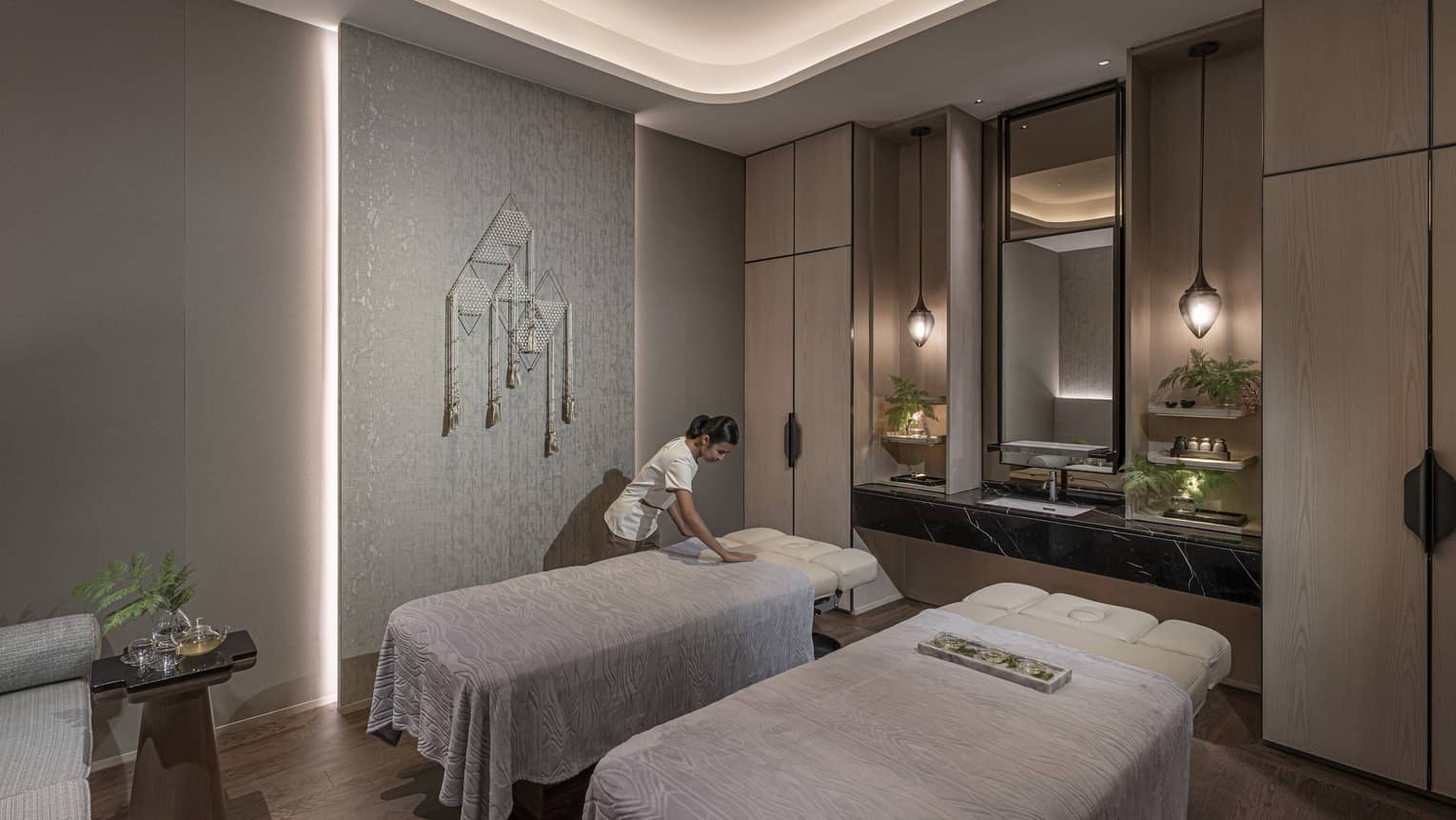 Massage therapist prepares a couples treatment room