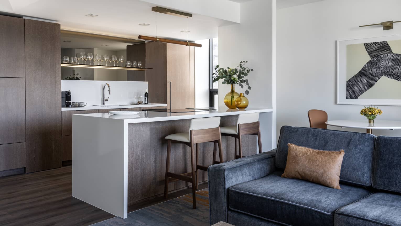 Kitchen area with white island, two chairs, wooden cabinets