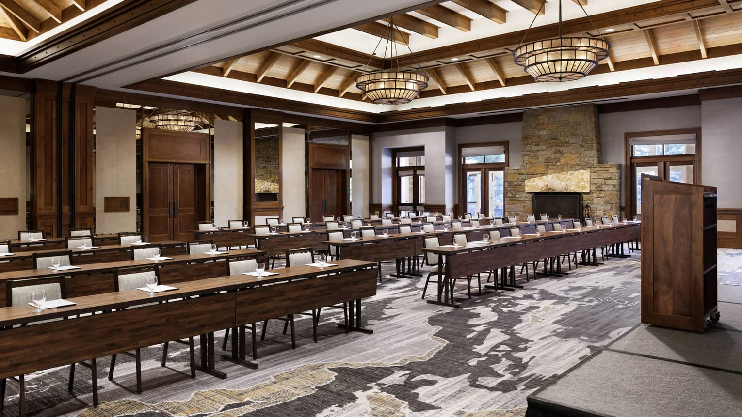 A large room with long tables and light coloured chairs, a podium and a stage.