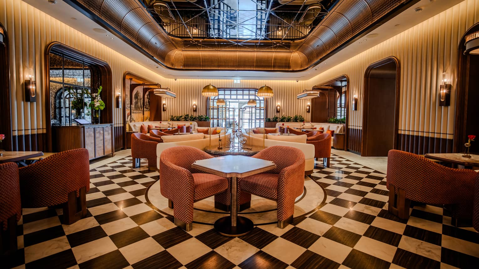 Restaurant dining room with black-and-white checkered flooring, white tables and plush mauve upholstered chairs