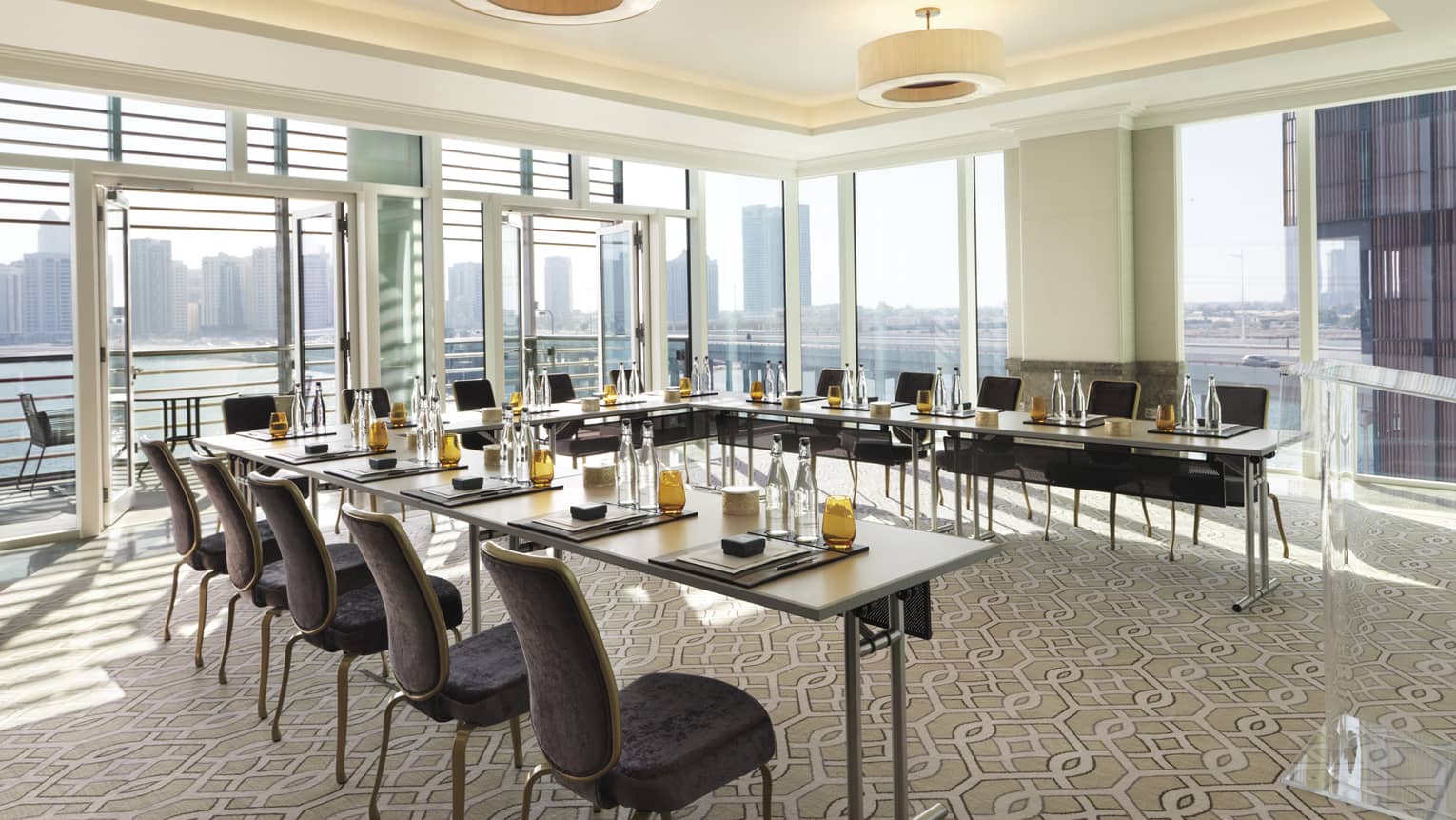 Velvet chairs around modular meeting table in sunny corner boardroom with glass walls, balcony