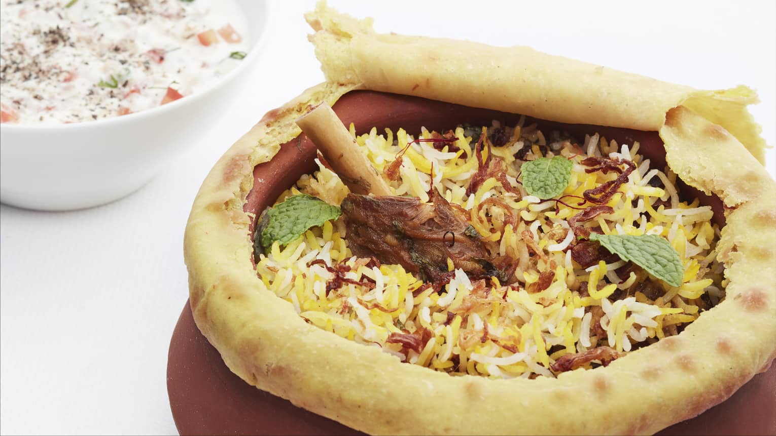 Close-up of Hyderabadi Dum Gosht Biryani rice and meat in pastry-covered pot