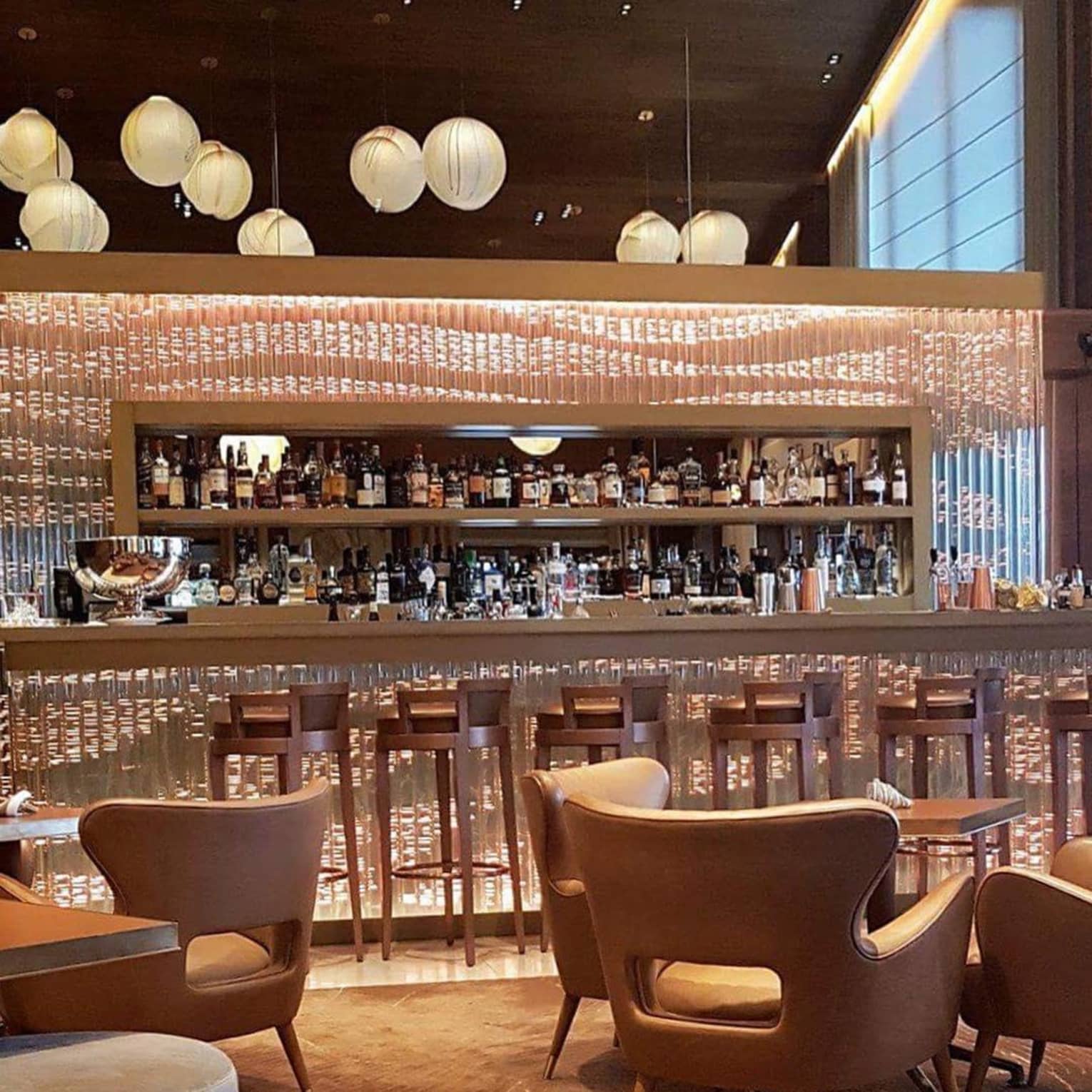 Stools at glass bar, mid-century style lounge chairs