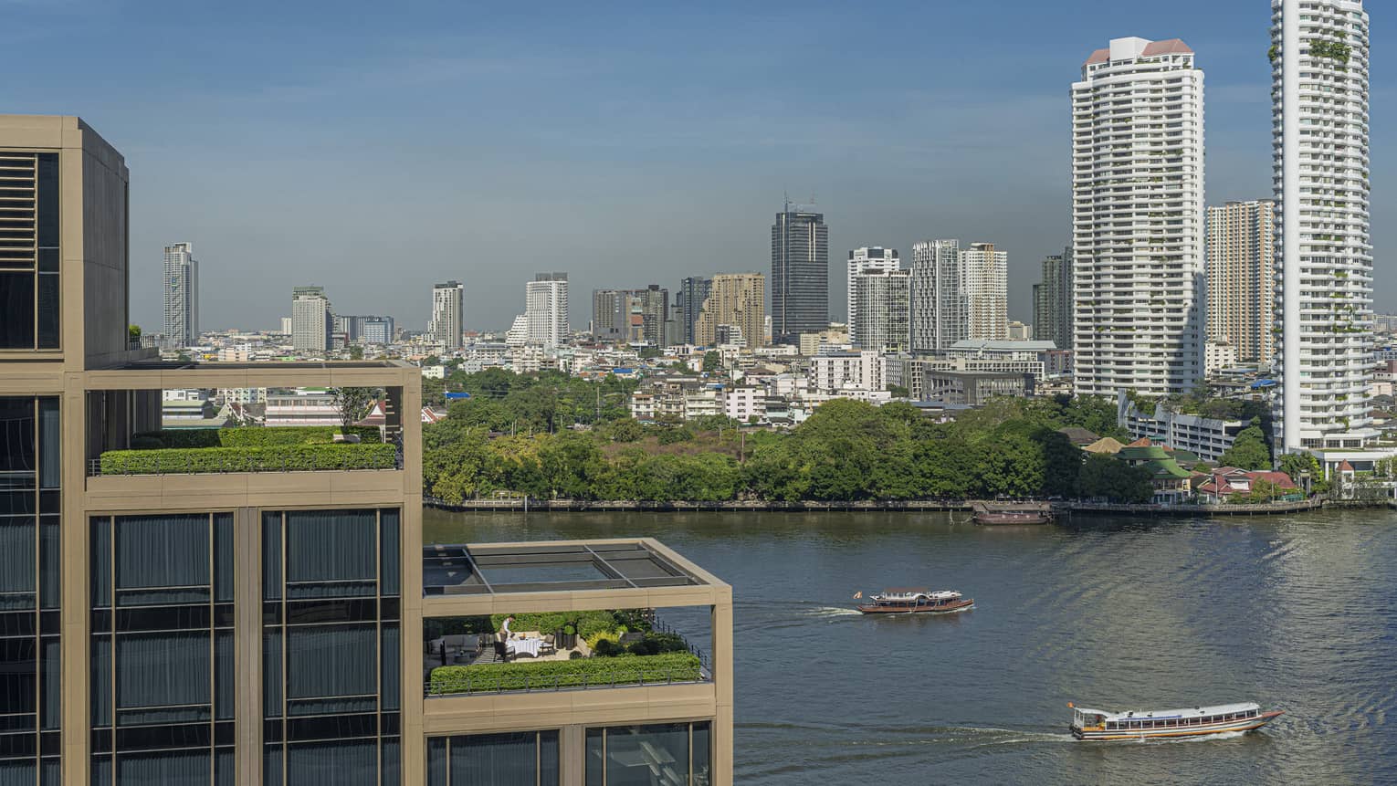 Hotel suites' outdoor patios, terraced on building, overlooking the Chao Phraya River and city