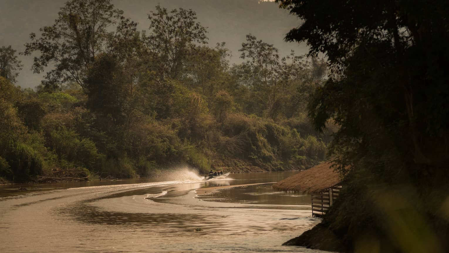 Longtail boat sprays water as it zips down the Ruak river