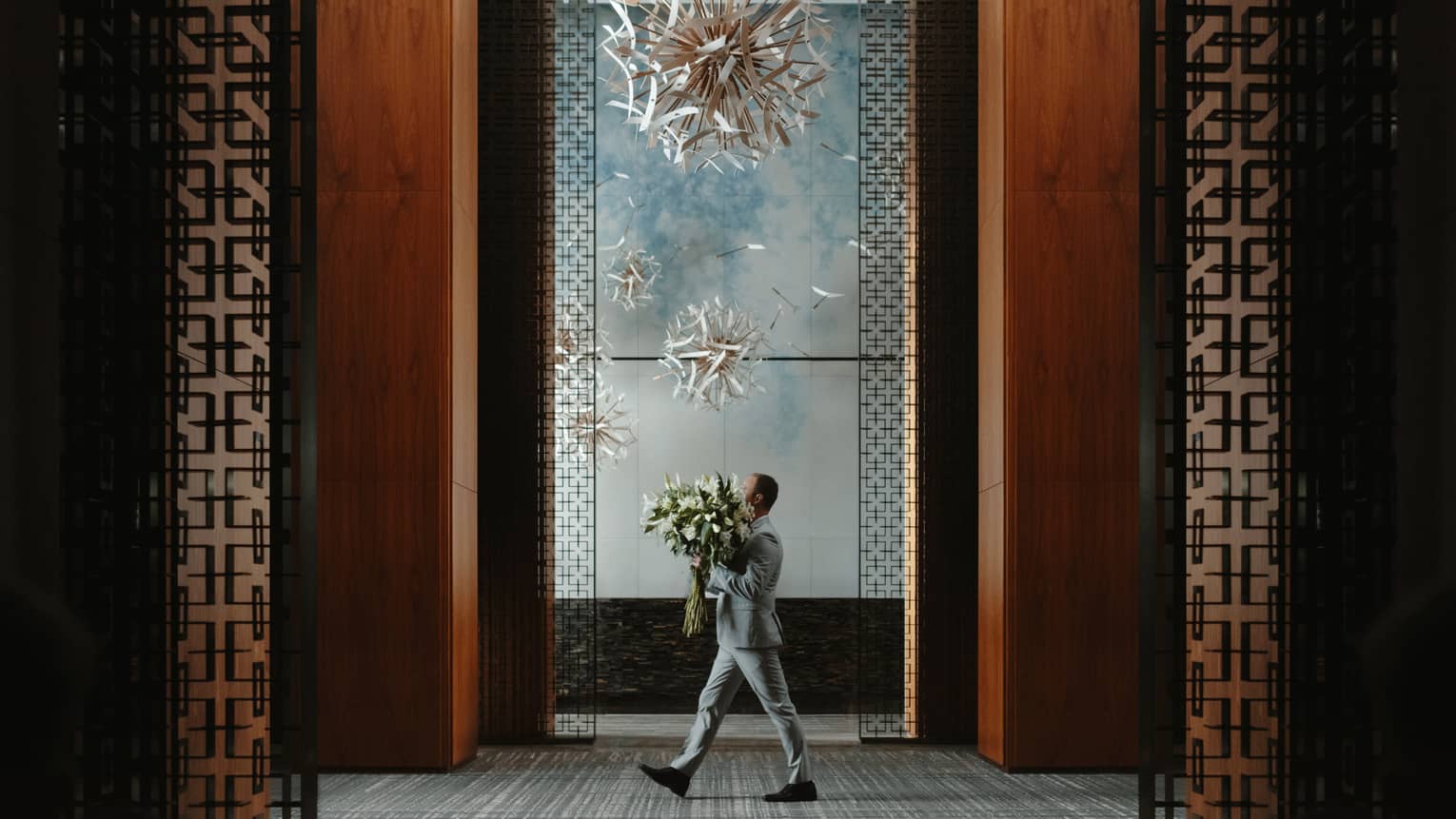 Man carries large floral arrangement through lobby of Four Seasons Hotel Toronto