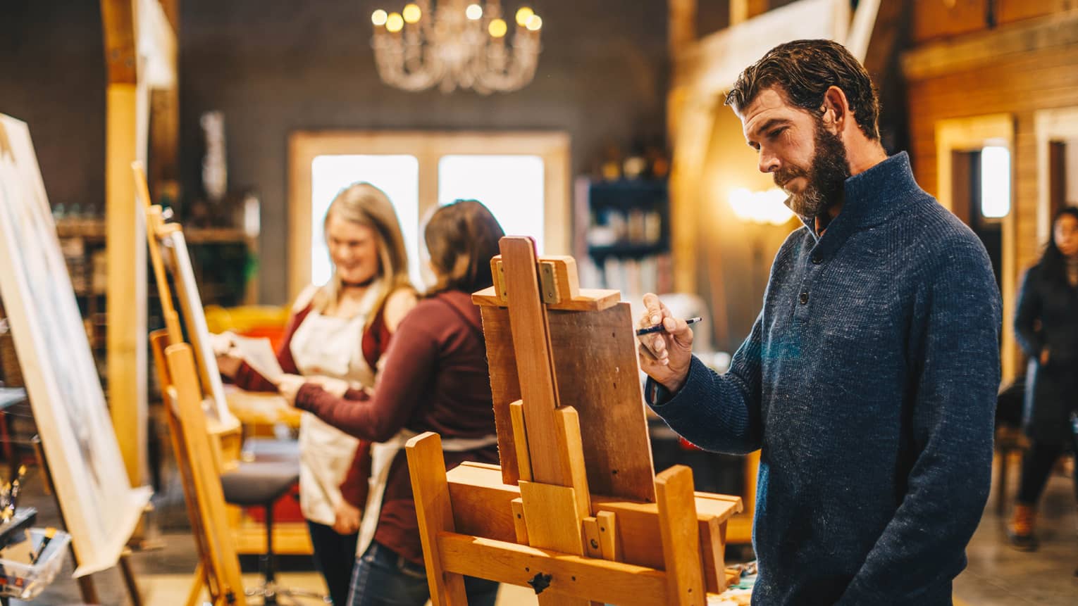 A man uses an easel and paints during a class