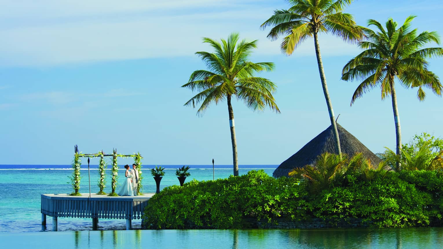 Wedding ceremony, bride and groom stand on small deck over lagoon at Pool Island