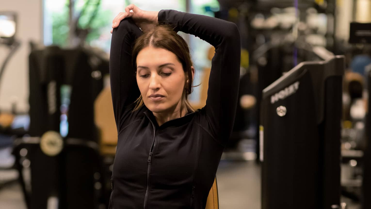 Guest stretching while sitting on an exercise machine.