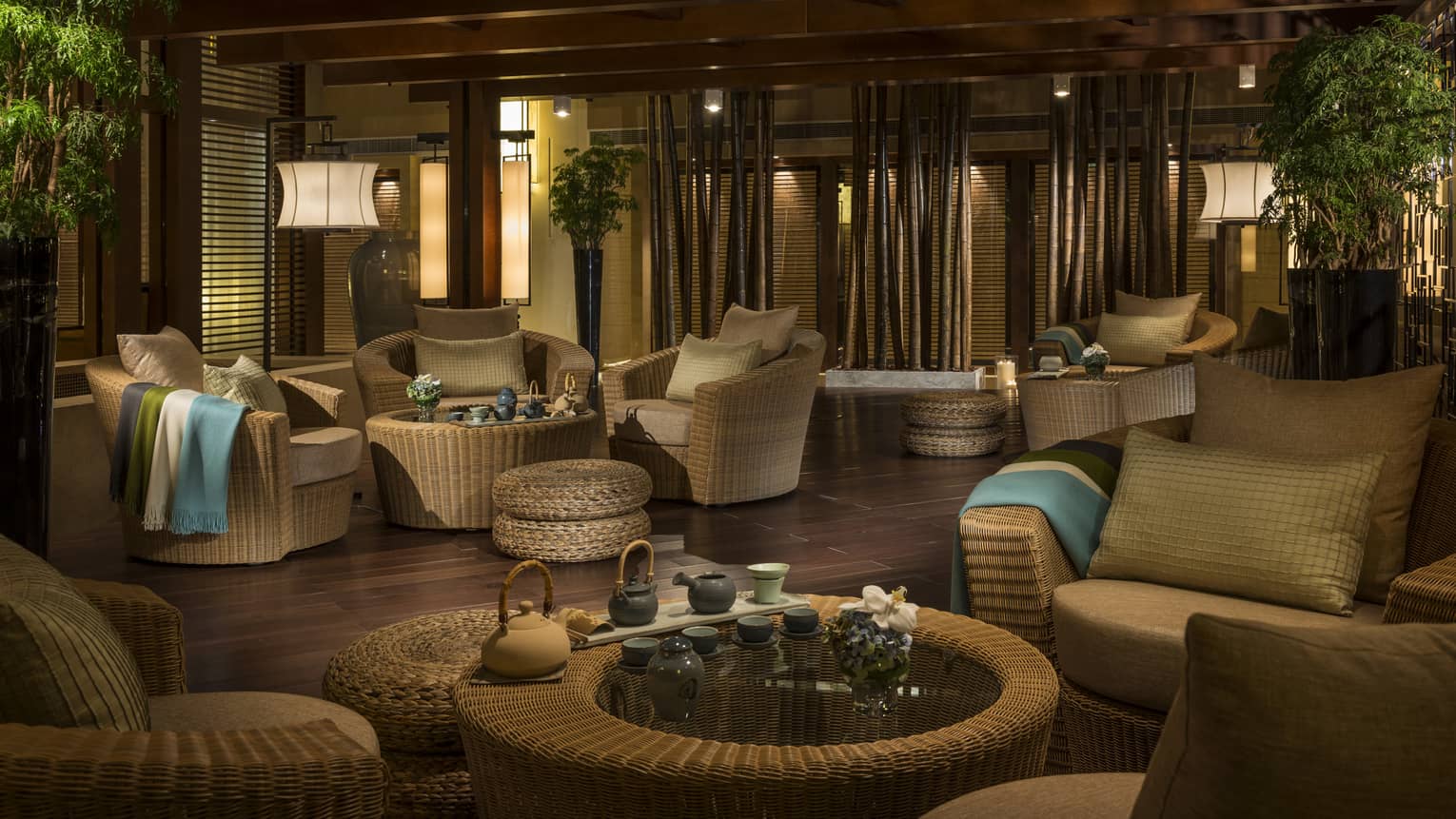 Dimly-lit Tea Garden lounge with light wicker furniture, tea service on tables