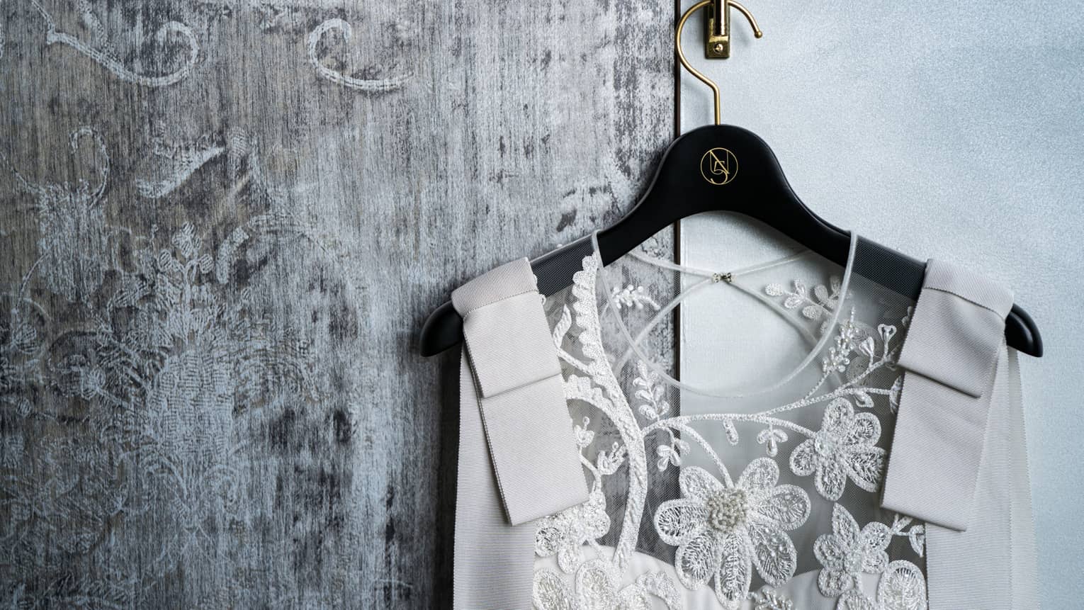 Close-up of wedding dress on hanger with lace flower bodice