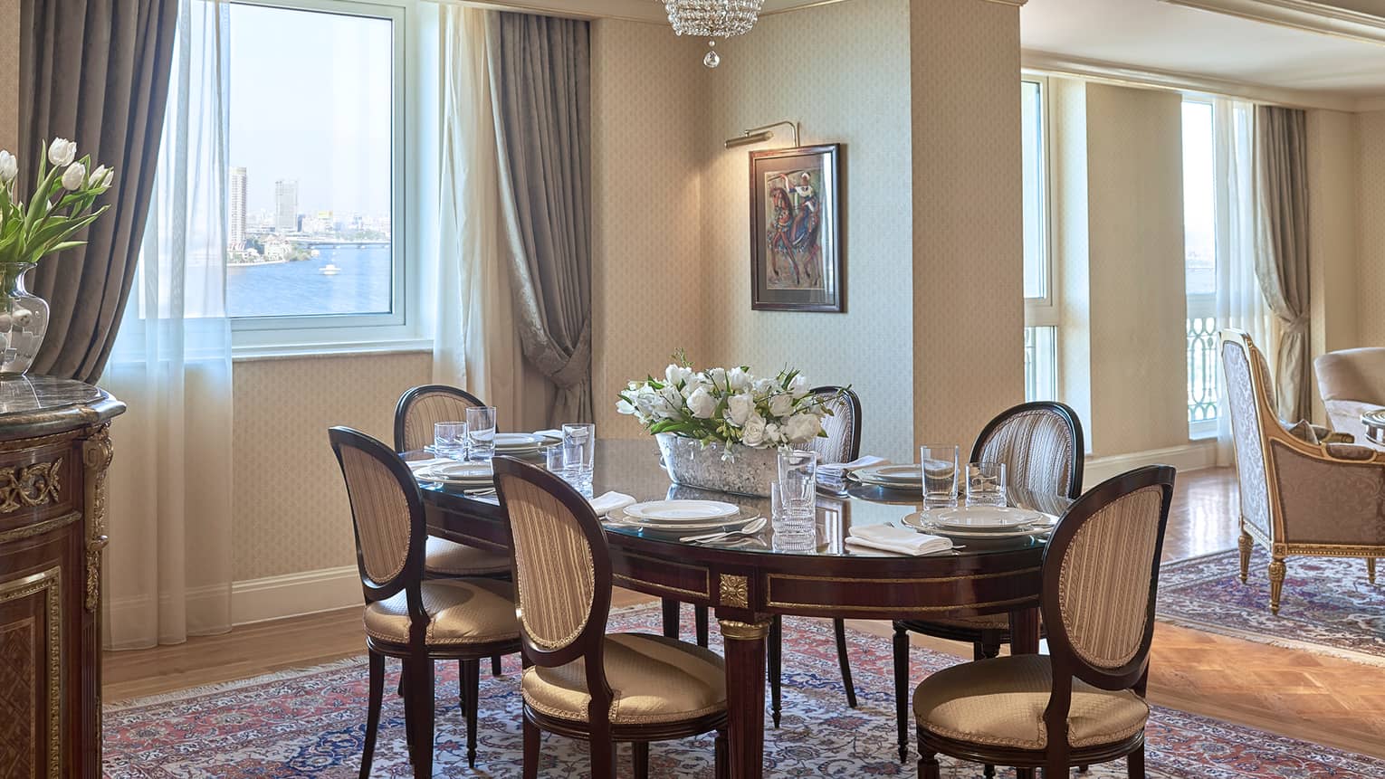 Presidential Suite elegant dining table with antique-style chairs, fresh white flowers, small window with Nile view